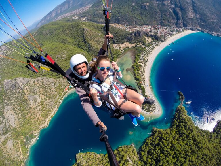 couple-of-people-flying-on-a-paraglide-over-the-turquoise-sea-and-beach