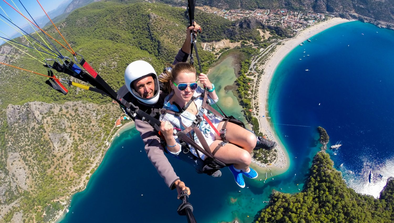 couple-of-people-flying-on-a-paraglide-over-the-turquoise-sea-and-beach